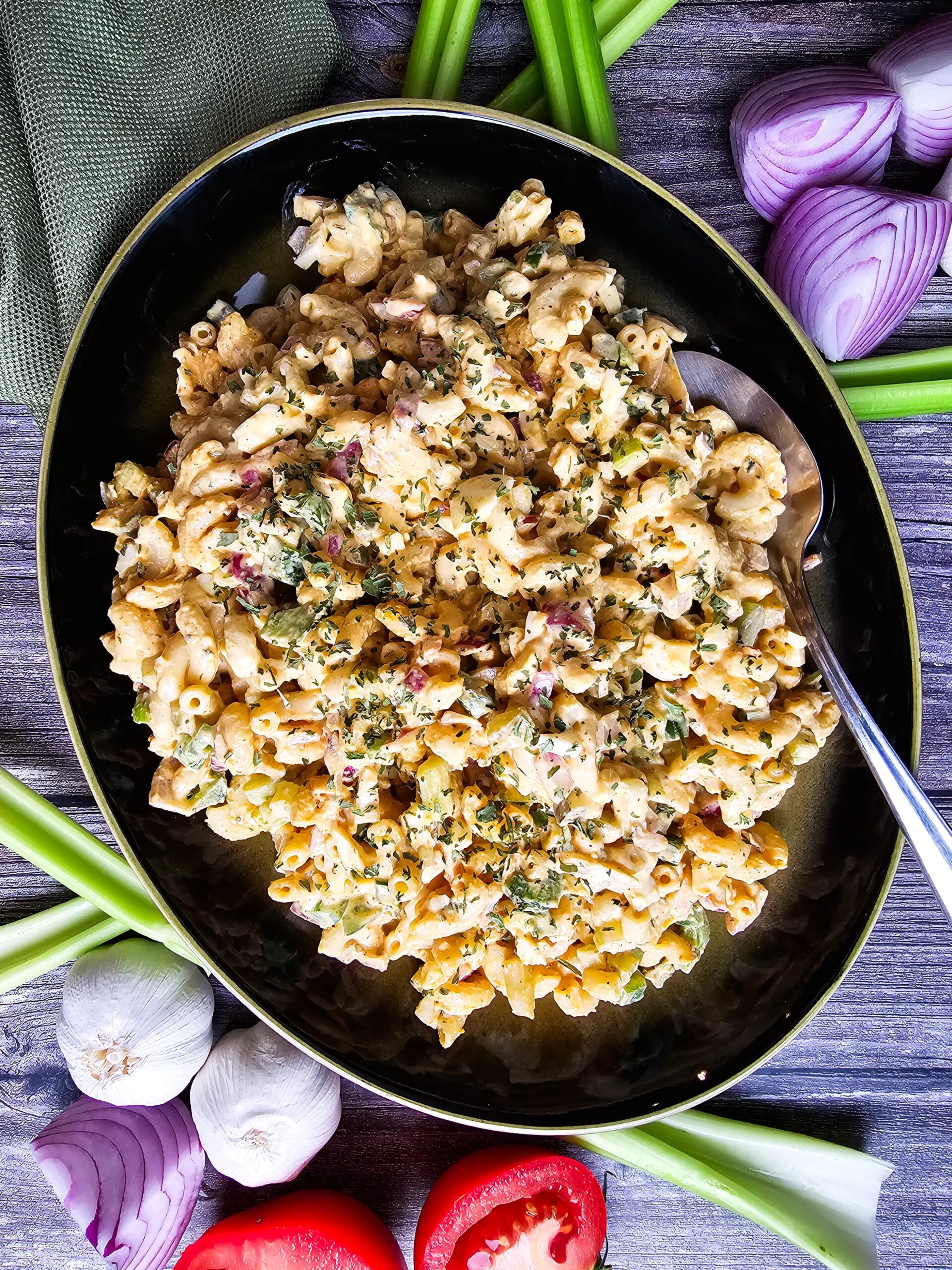 Family-sized serving of creamy veggie pasta salad on a rustic outdoor table.