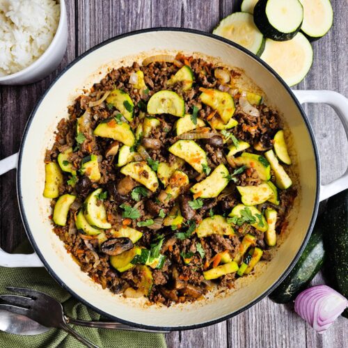 Quick and easy ground beef stir fry in a skillet, ready to serve with rice and chopsticks.