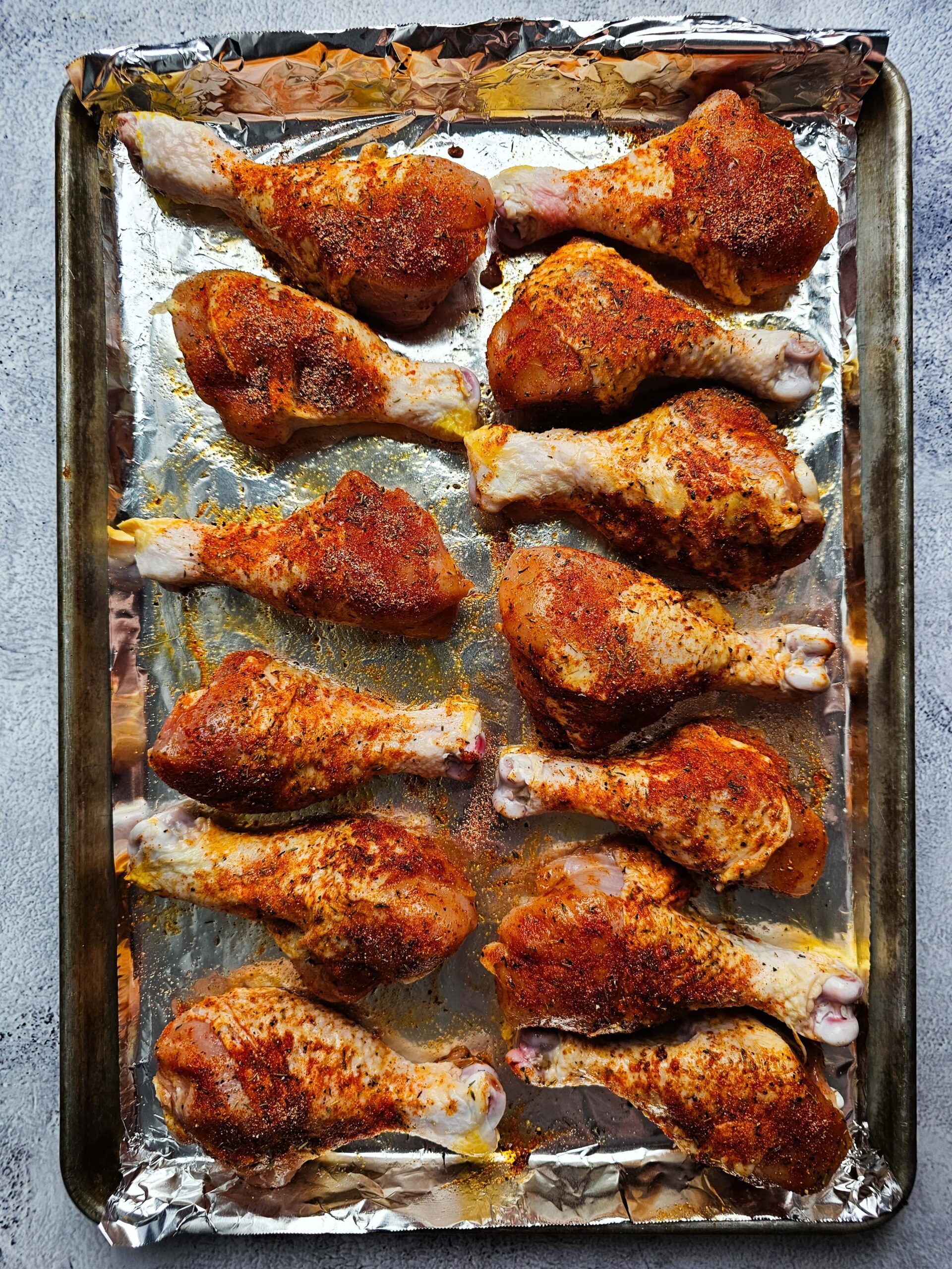 SEASONED CHICKEN LEGS ON A LARGE BAKING SHEET