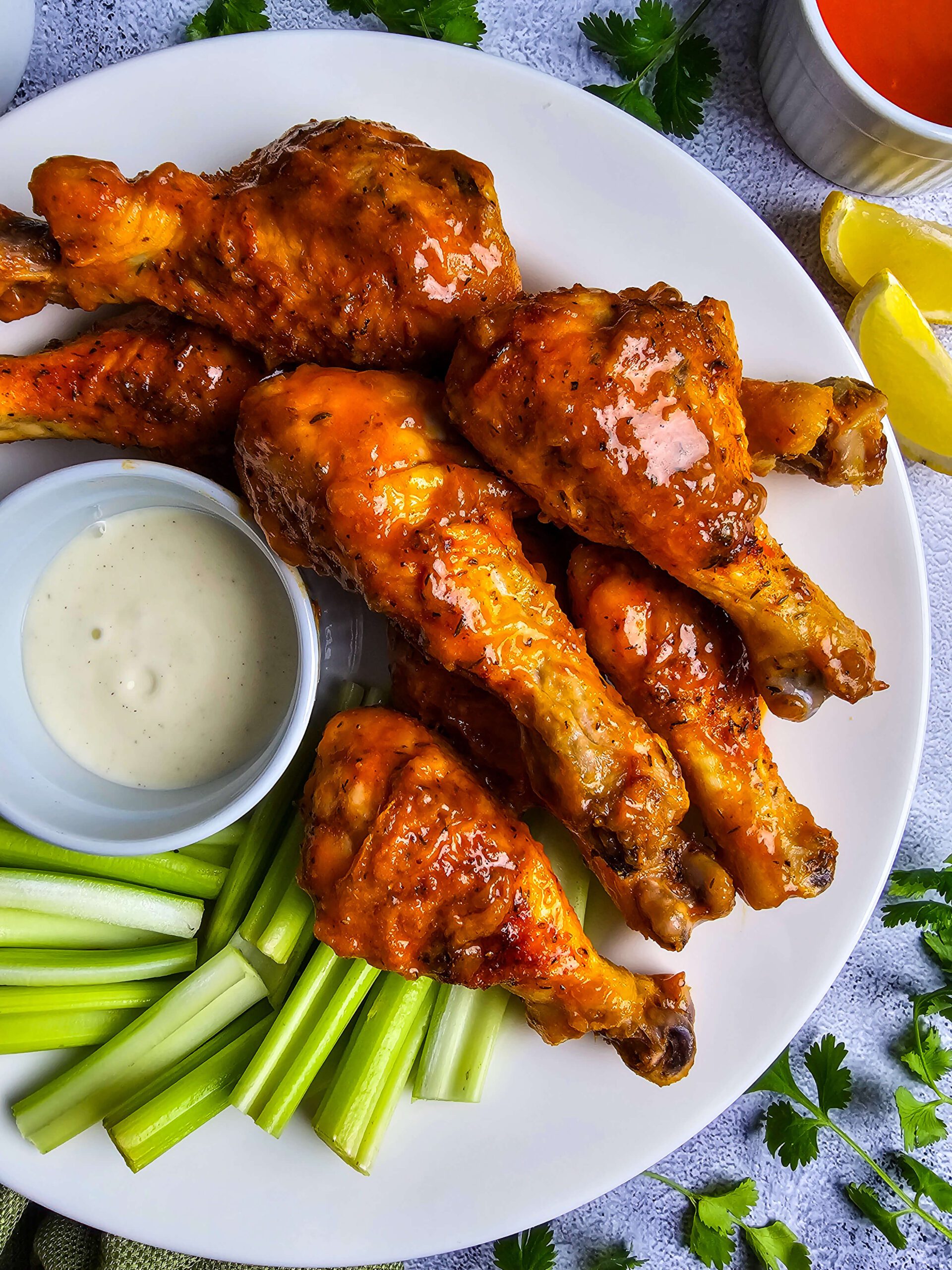 Close-up of spicy chicken drumsticks with dipping sauce and a summer broccoli salad