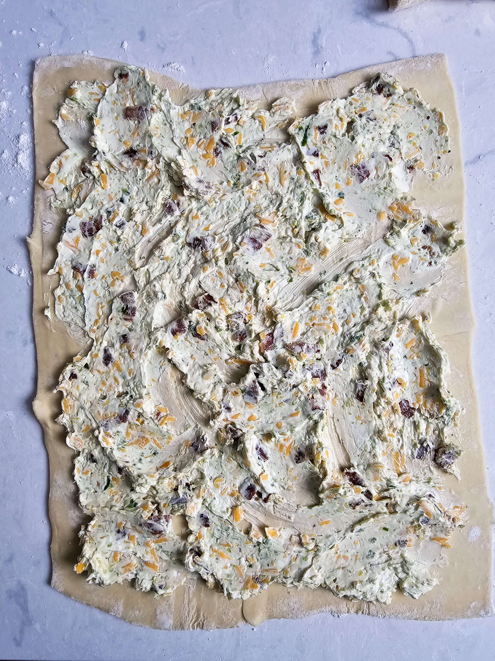 ROLLED OUT PUFF PASTRY WITH THE FILLING EVENLY SPREAD OUT
