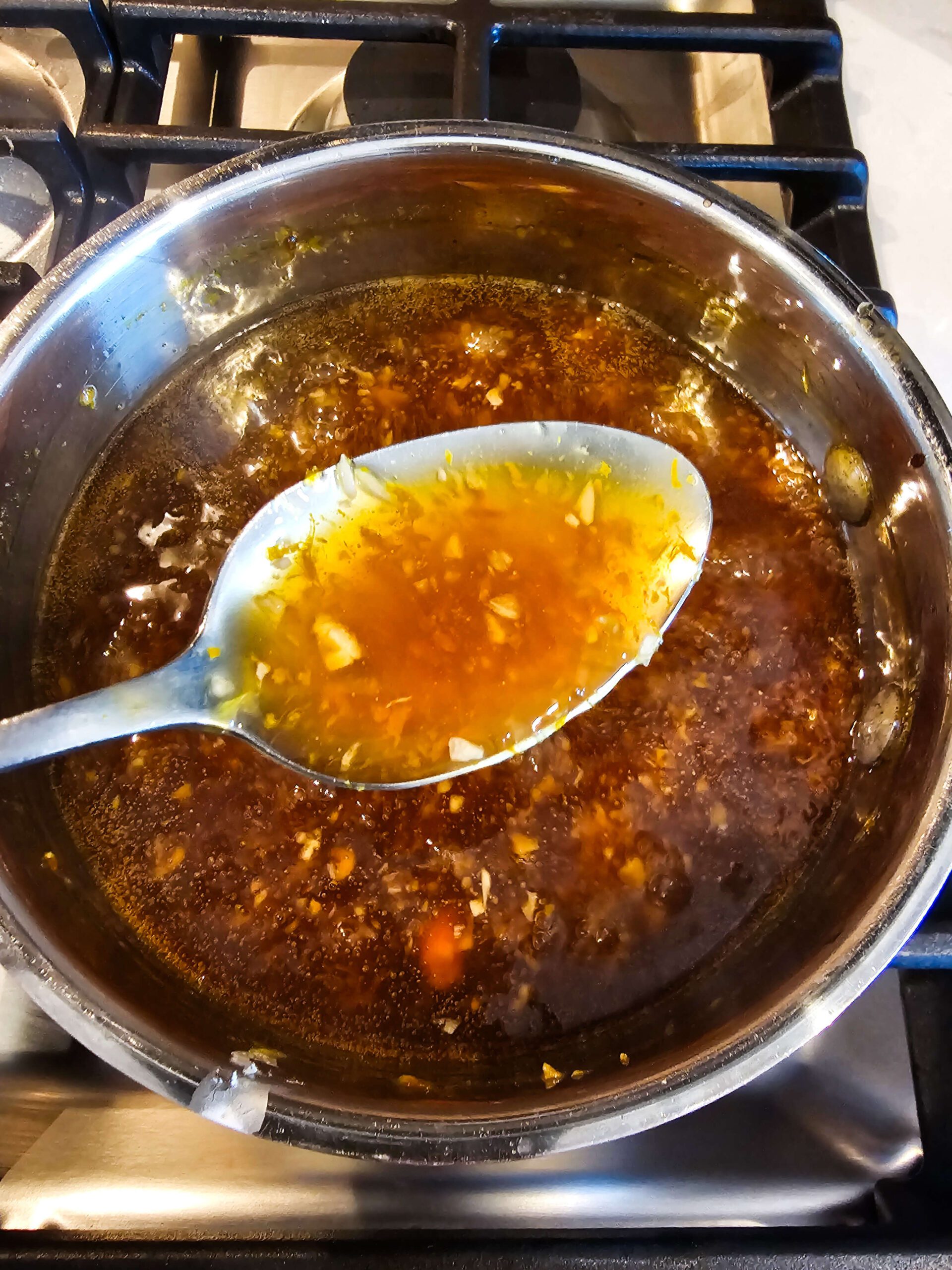 ORANGE SAUCE SIMMERING IN A SMALL SAUCE PAN