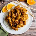 PLATE FULL OF ORANGE CHICKEN ON A BED OF RICE