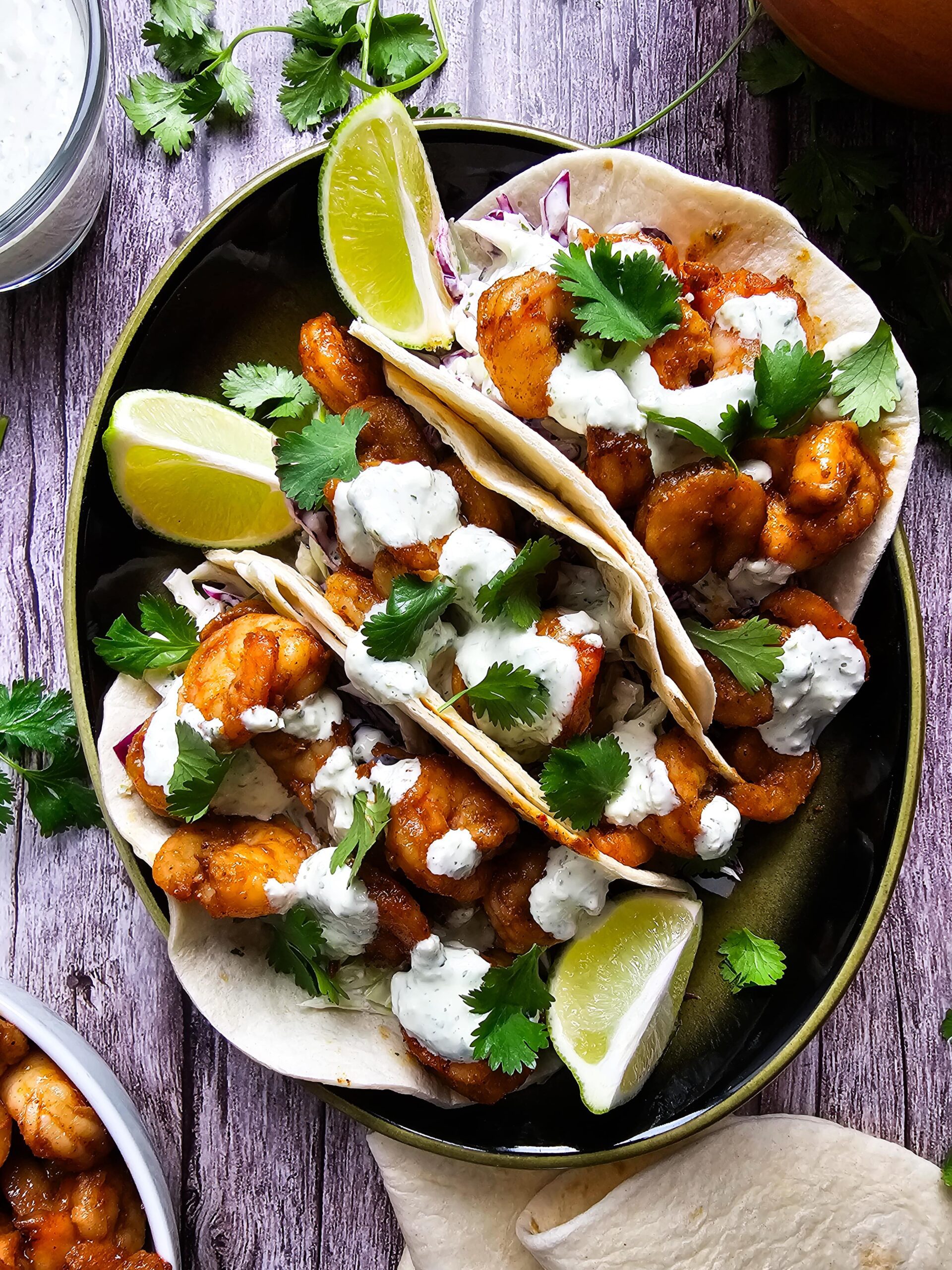 ASSEMBLE THE TACOS ON A LARGE GREEN PLATER AND GARNISHED WITH LIMES AND CILANTRO