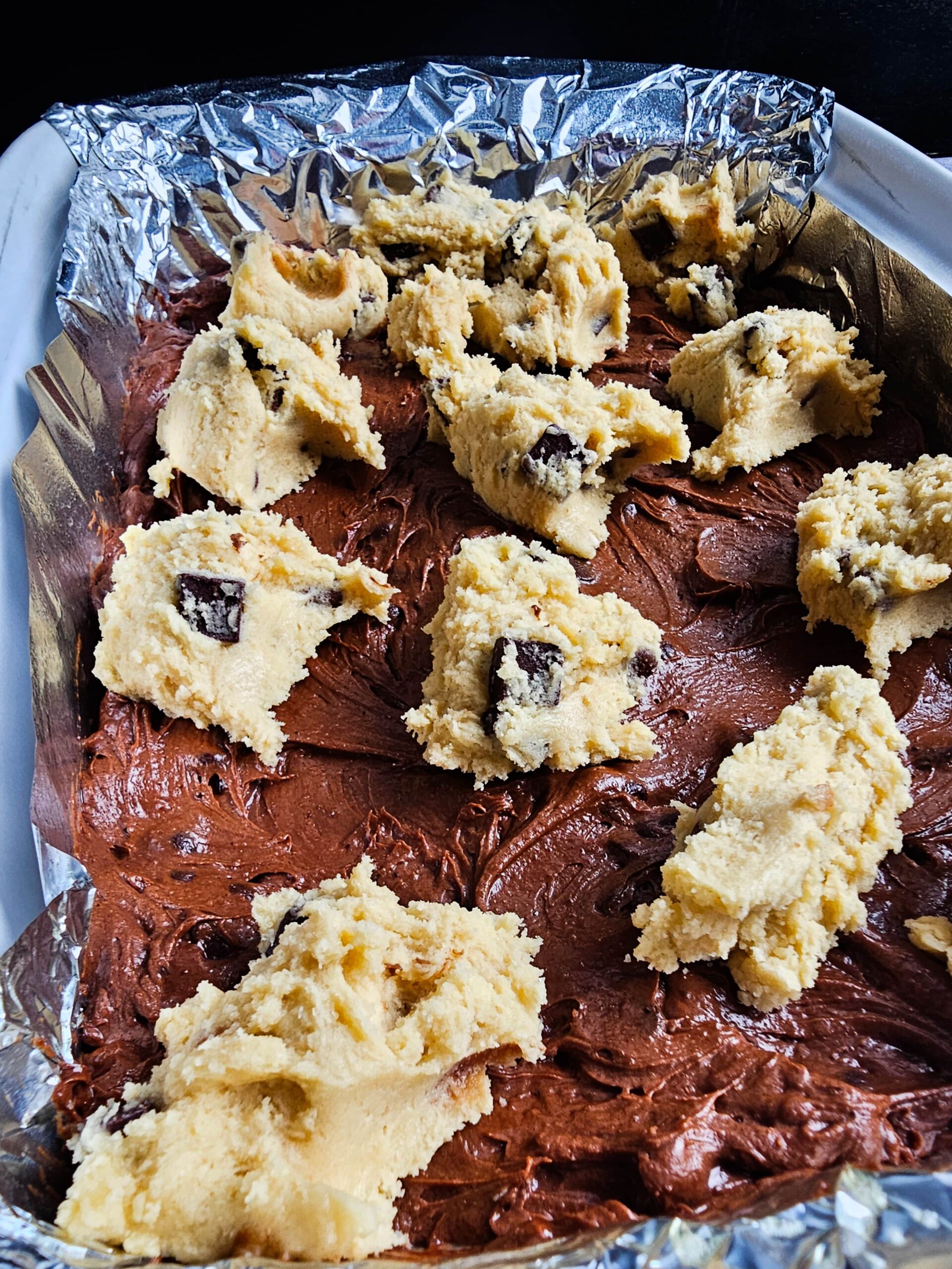 DOLLOP THE COOKIE DOUGH ON TOP OF THE BROWNIE BATTER