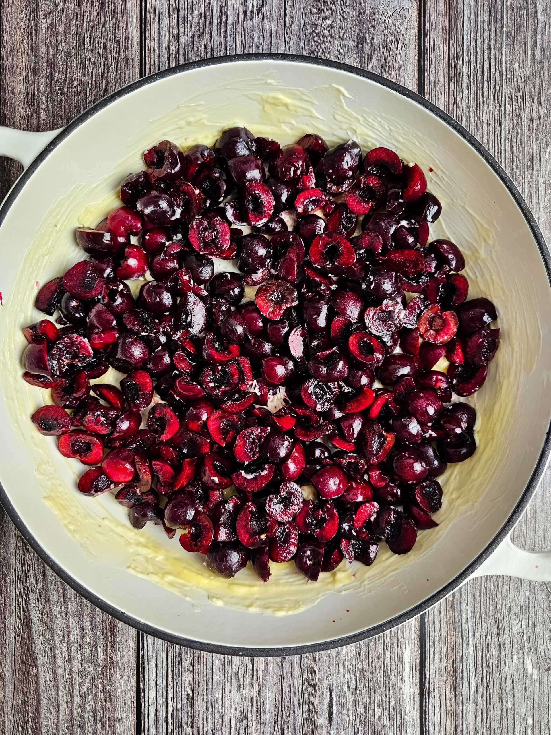 LARGE WELL BUTTERED SKILLET WITH THE CLEANED CHERRIES EVENLY SPREAD ON THE BOTTOM