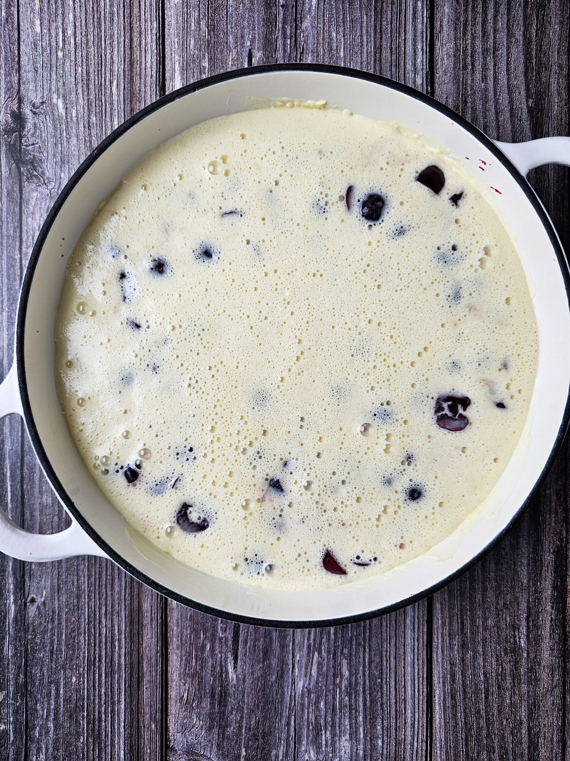 LARGE CAST ENAMEL SKILLET AND THE BATTER IS POURED OVER THE CHERRIES
