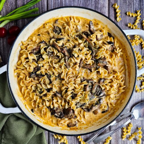 LARGE SKILLET FULL OF THE MUSHROOM STROGANOFF SET ON A RUSTIC WOODEN TABLE
