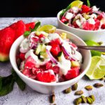 LARGE WHITE BOWL FILLED WITH WATERMELON SALAD AND DRIZZLED WITH YOGURT LIME DRESSING