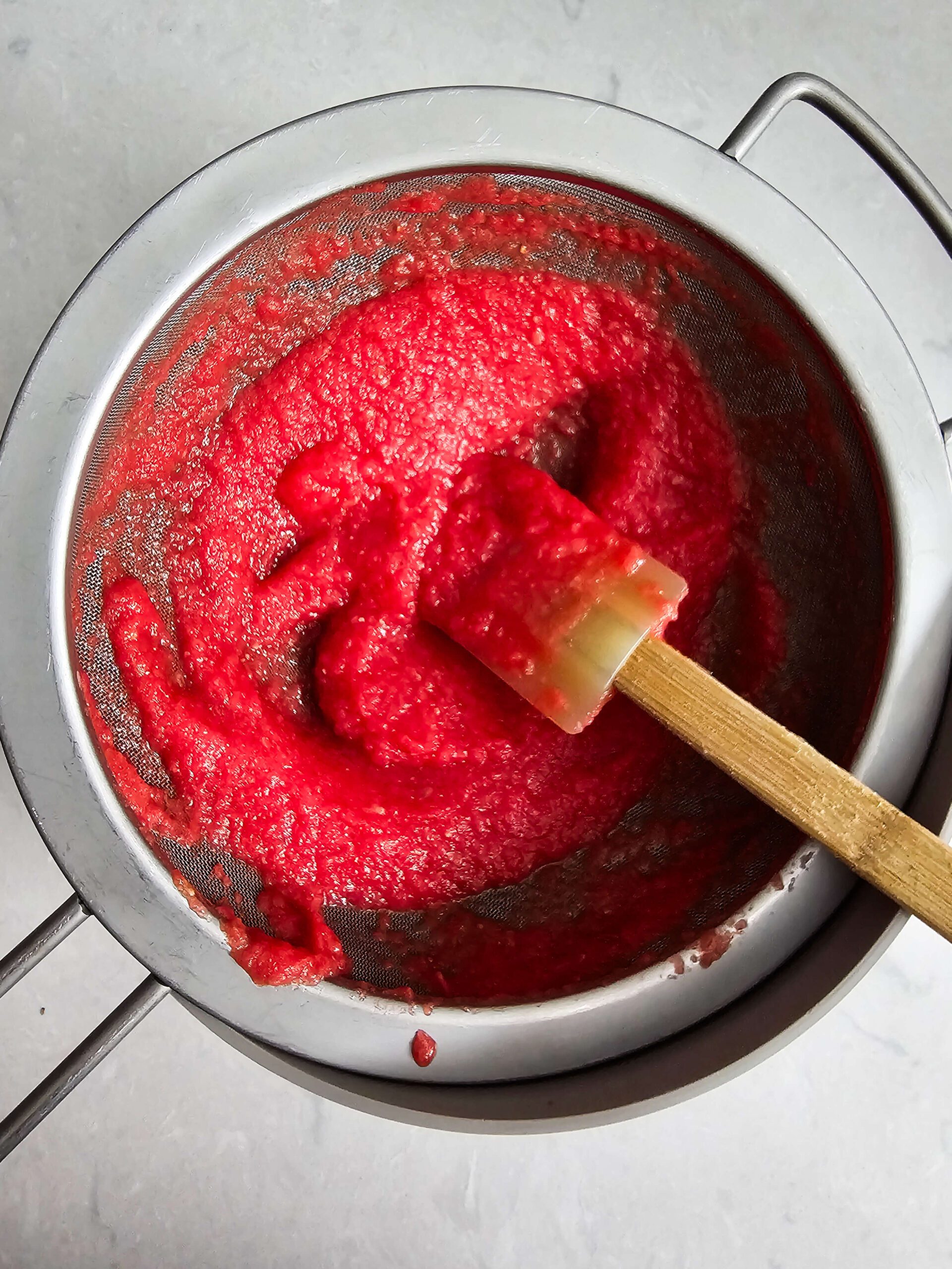 pushing the blended watermelon juice through a strainer