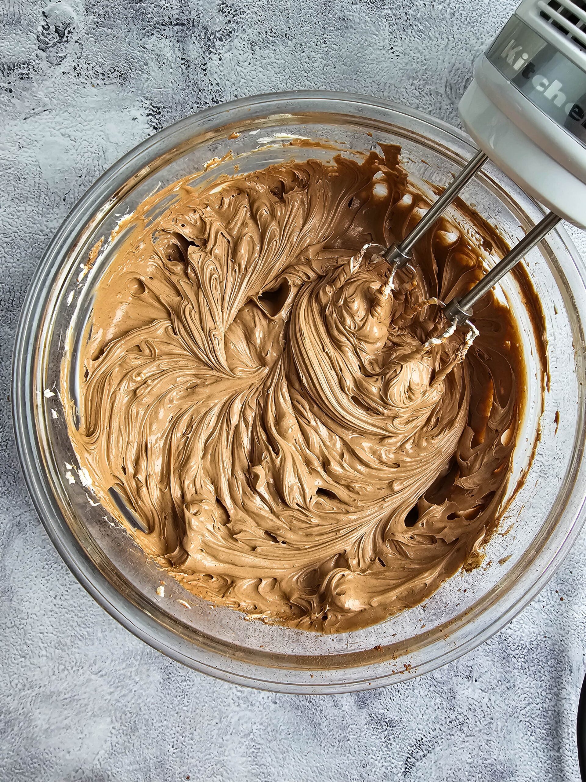 CLEAR BOWL OF WHIPPED CREAM CHEESE WITH SUGAR AND COCO POWDER ADD