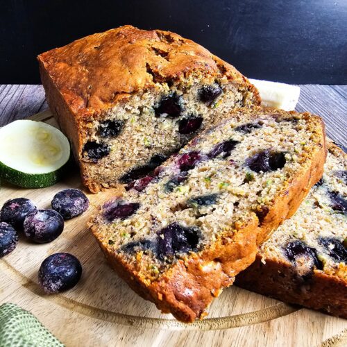 slices of blueberry banana zucchini bread on wooden cutting board