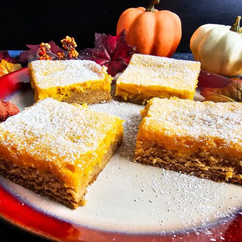 PLATE FULL OF PUMPKIN BUTTER BARS SPRINKLED WITH POWERED SUGAR