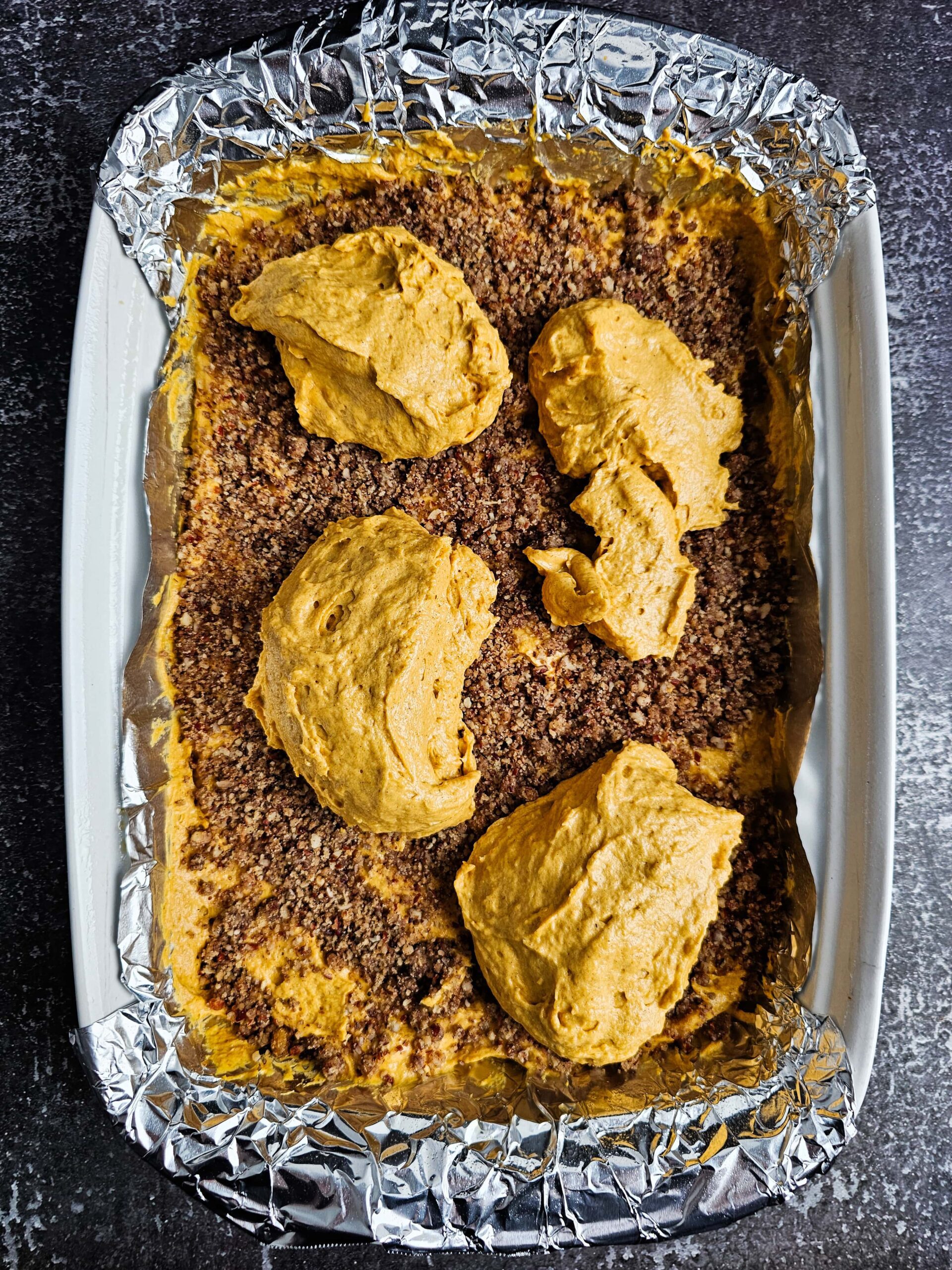 IN A WHITE 9X13 BAKING PAN SPREAD HALF THE IN BAKING DISH AND HALF THE CINNAMON TOPPING AND THEN THE OTHER HALF.
