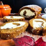 Simple Homemade Pumpkin Roll with Sweet Cream Cheese Swirl sliced on a wooden cutting board