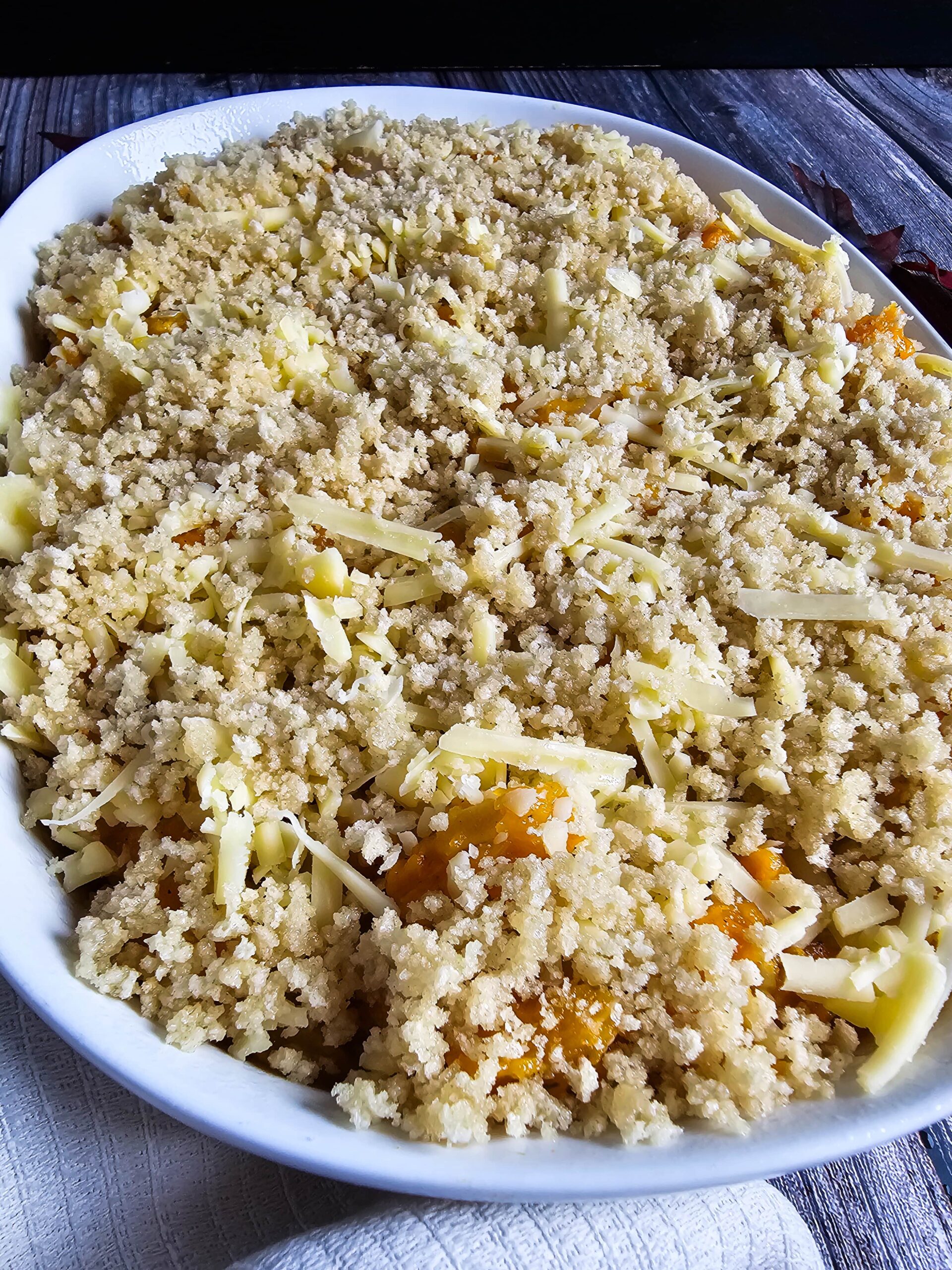 POUR THE MIXTURE INTO CASSEROLE DISH AND TOP WITH MORE CHEESE AND THE PANKO TOPPING MIXTURE.