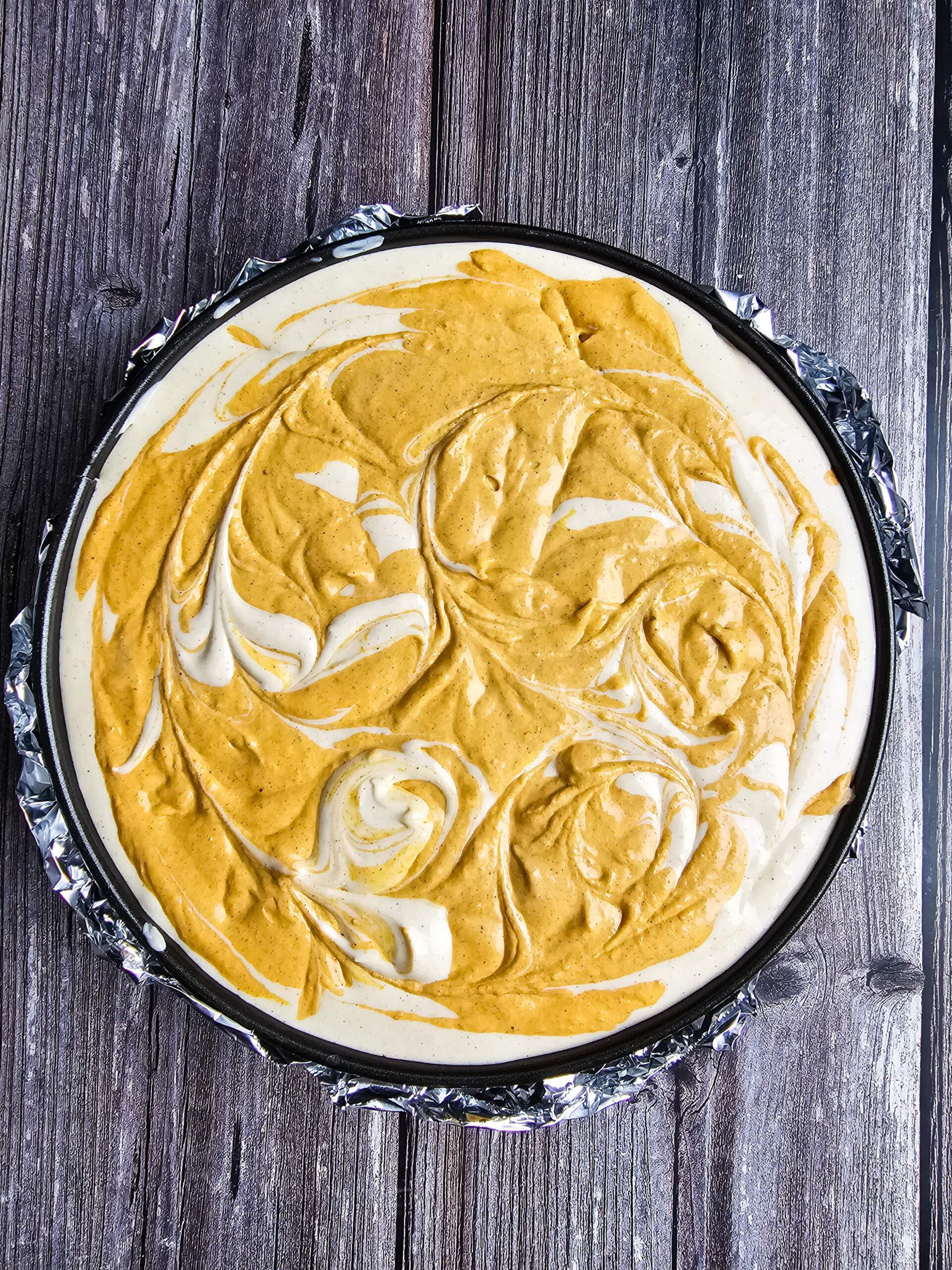 assembled cheesecake with pumpkin cheesecake filling swirled throughout