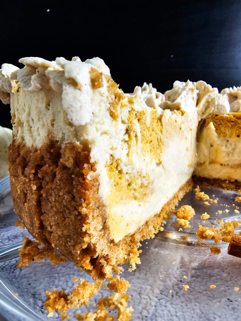 SIDE VIEW OF PUMPKIN SWIRL CHEESECAKE WITH A SLICE REMOVED