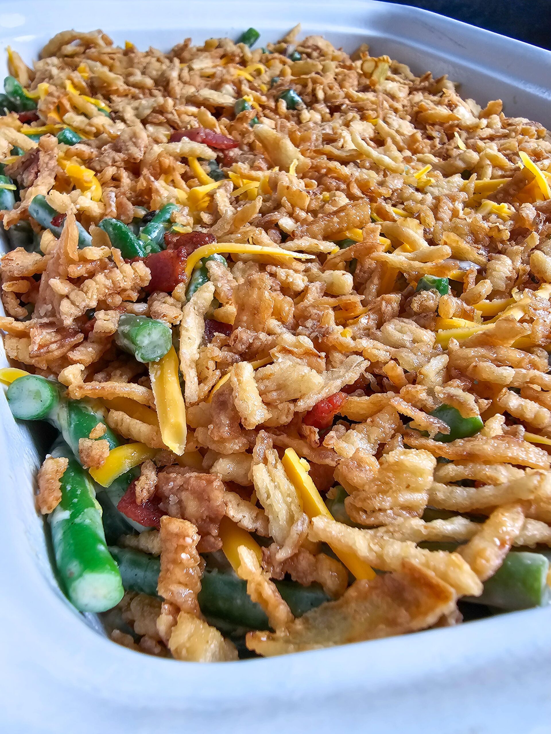 TRANSFER TO A BAKING DISH AND TOP WITH EXTRA CHEESE, CRISPY BACON AND FRENCH FRIED ONIONS