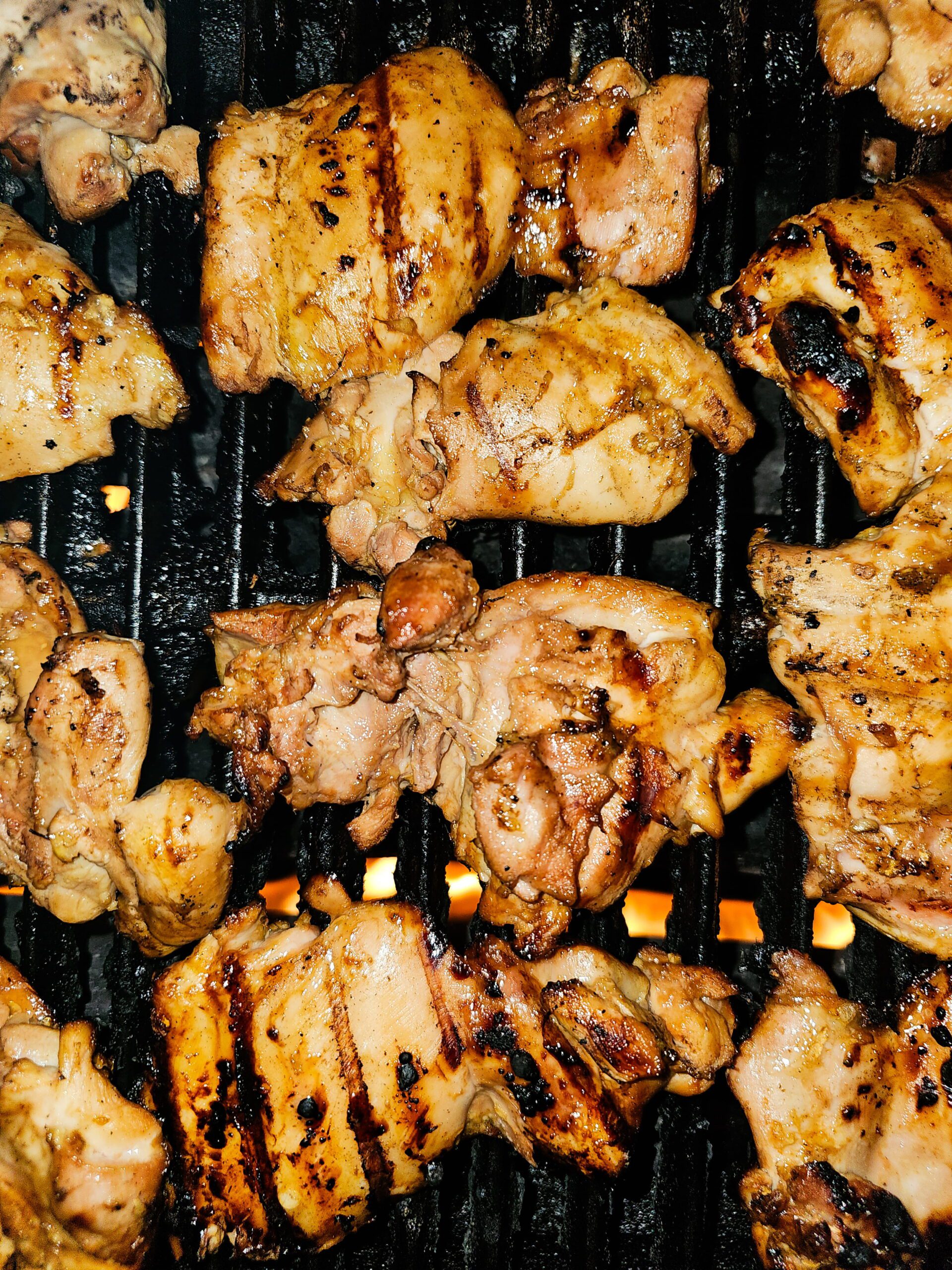 huli huli chicken thighs grilling on outdoor grill