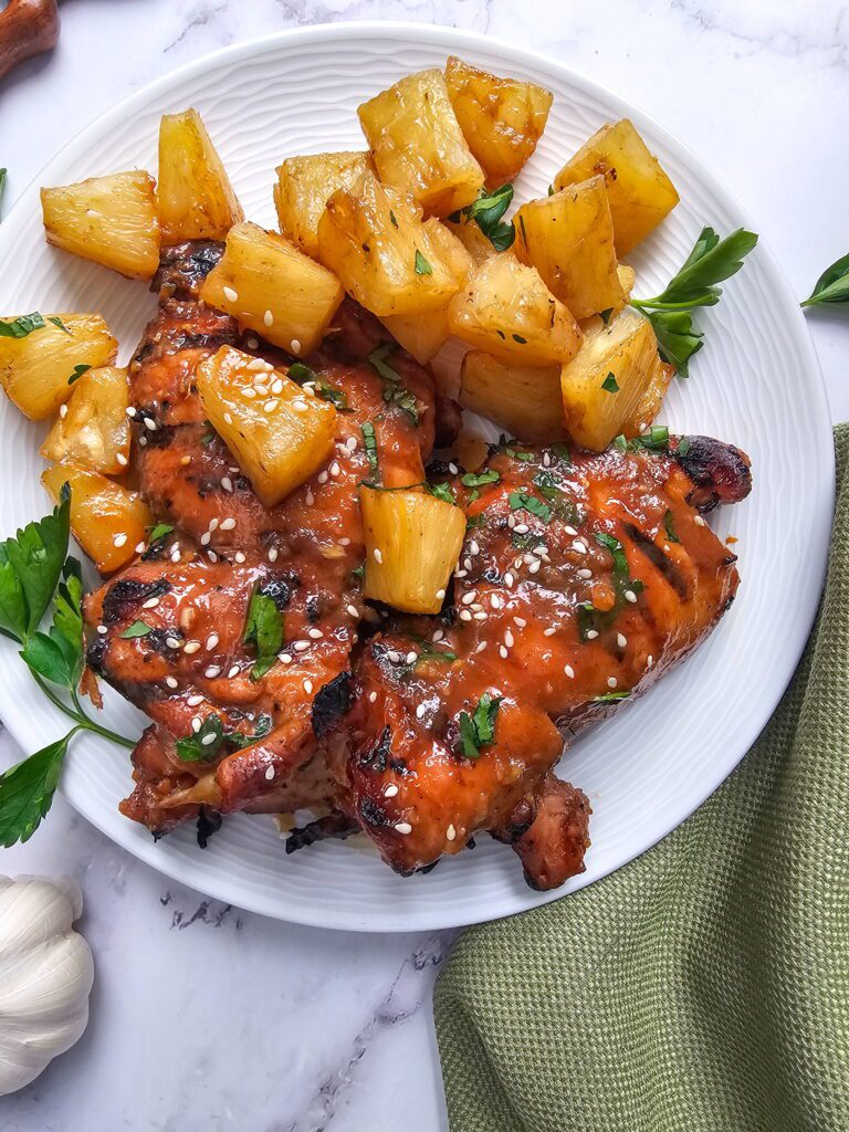 plate of huli huli chicken thighs with grilled pineapple
