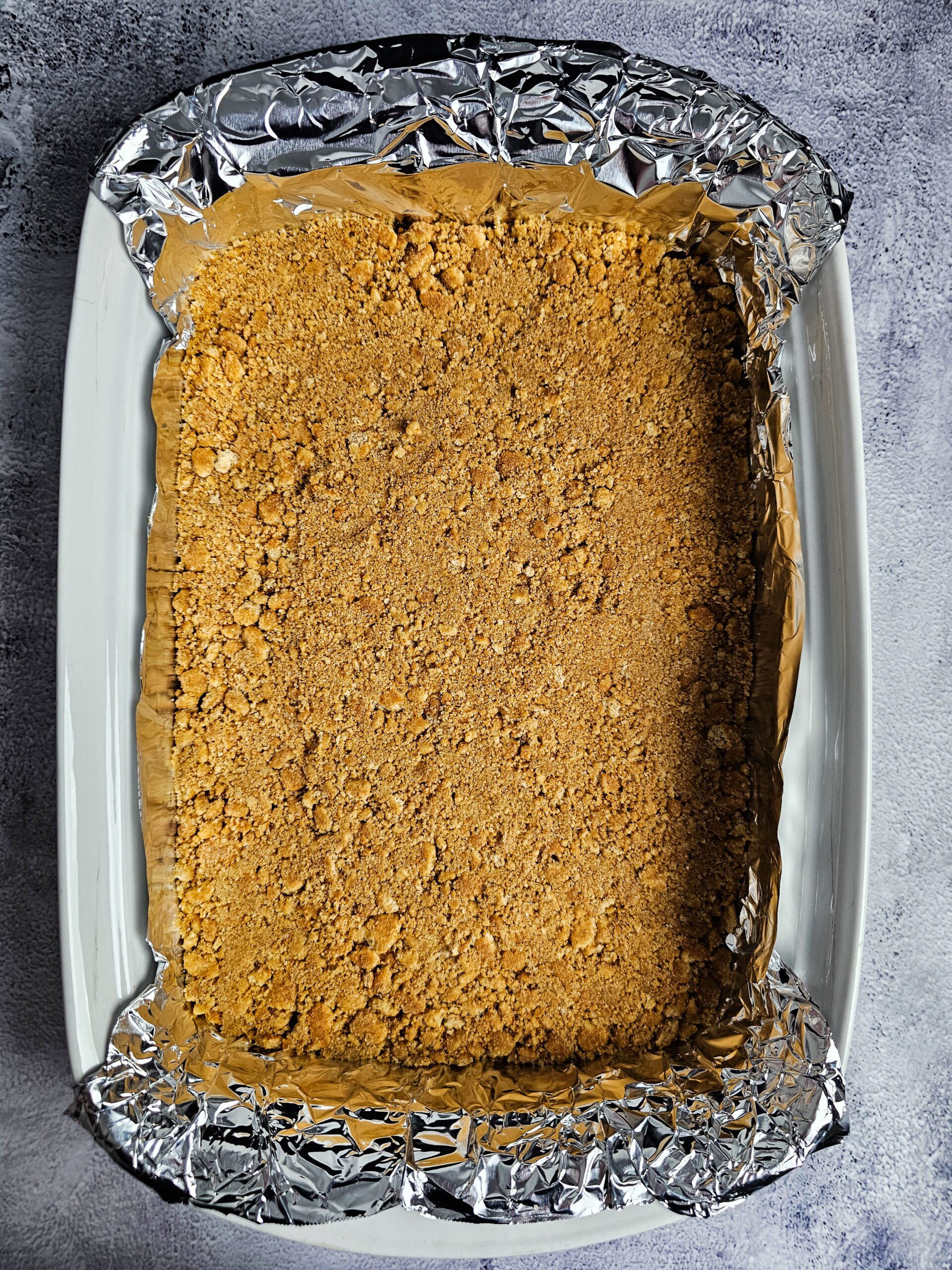 pressing graham cracker crust into 9x13 pan