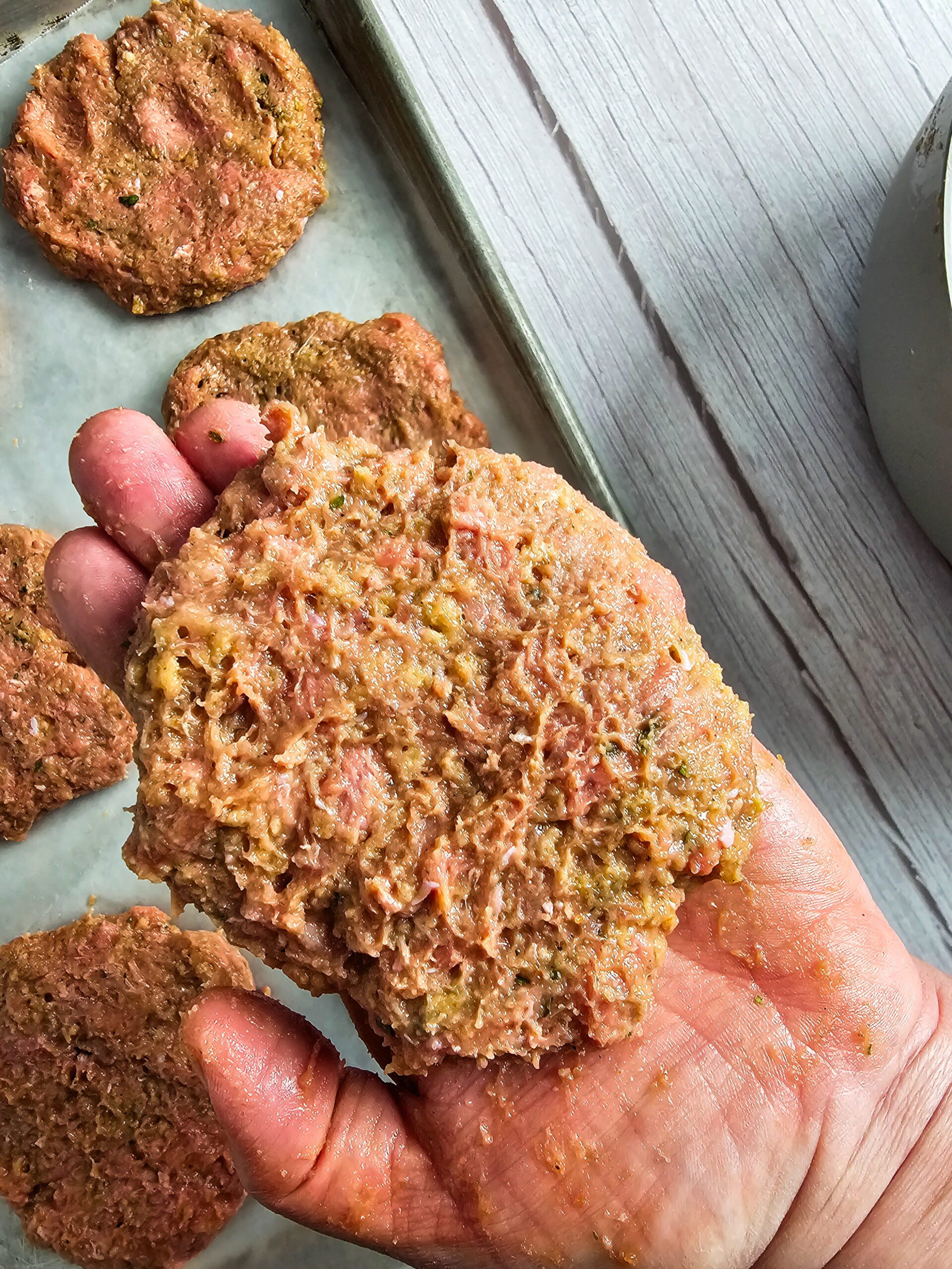 Formed turkey burger patties with thumb indent pressed in center on parchment lined sheet pan