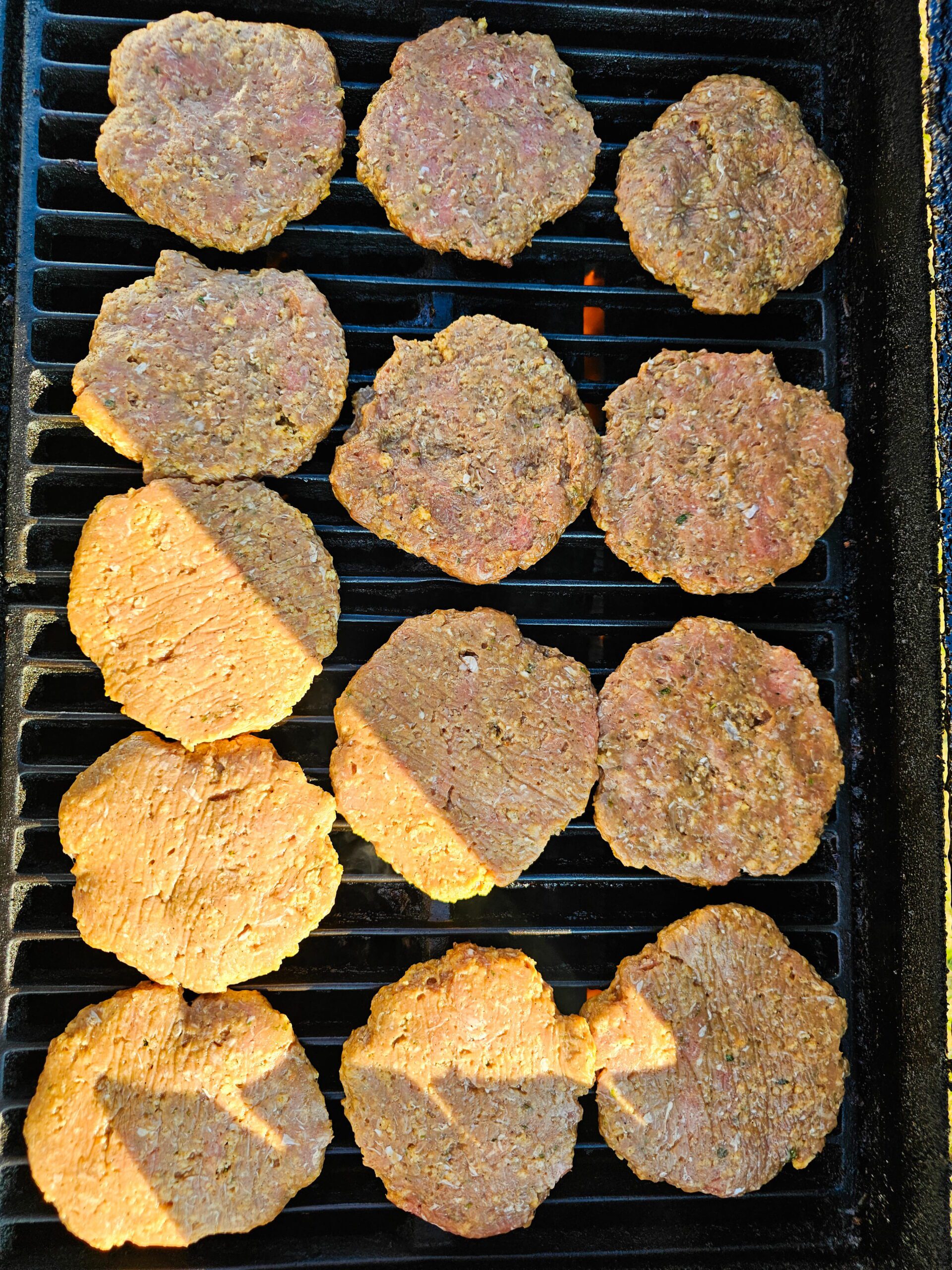 Turkey burgers cooking on a gas grill over medium heat with grill marks forming