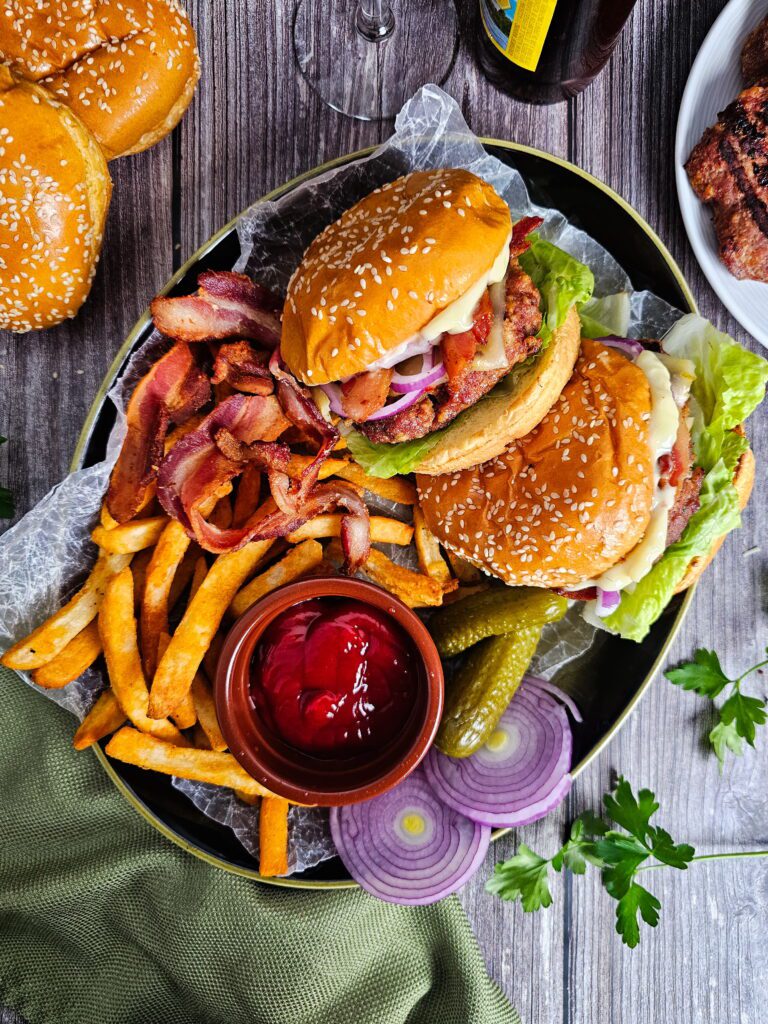 Juicy turkey burger on a toasted brioche bun with lettuce, tomato and red onion with french fries and a side of pickles