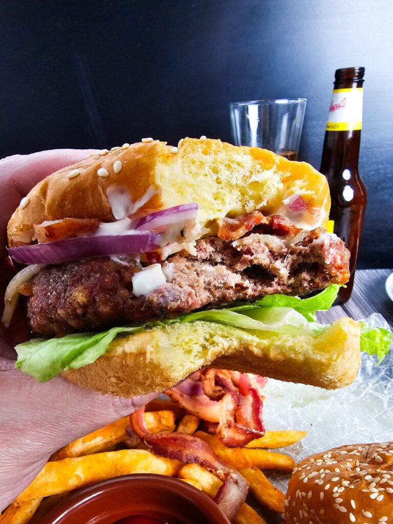 Juicy turkey burger on a toasted brioche bun with lettuce, tomato and red onion with a large bite taken