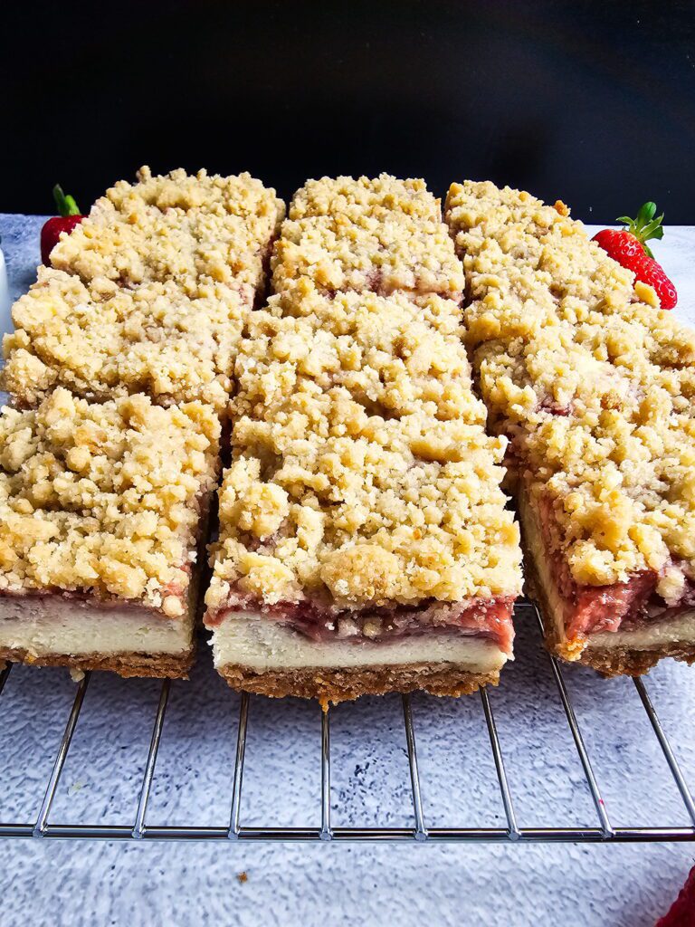 close up of strawberry cheesecake bar slice showing crumble topping