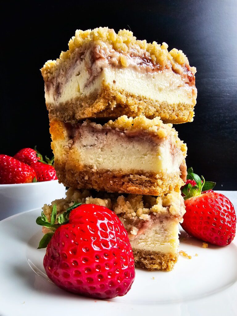 close up of strawberry cheesecake bar slice showing crumble topping