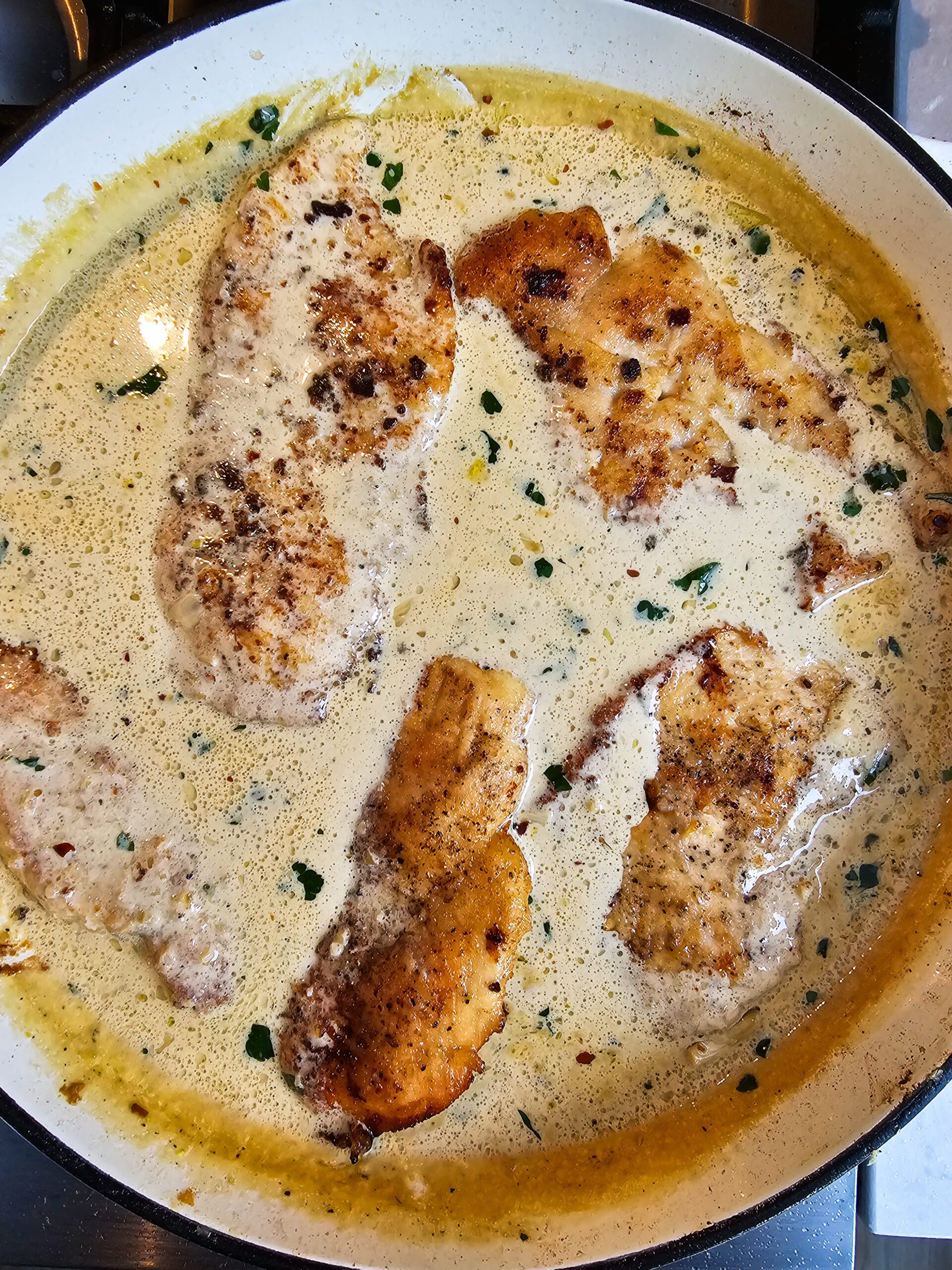 Seared chicken cutlets returned to creamy garlic skillet spooned with rich parmesan garlic cream sauce