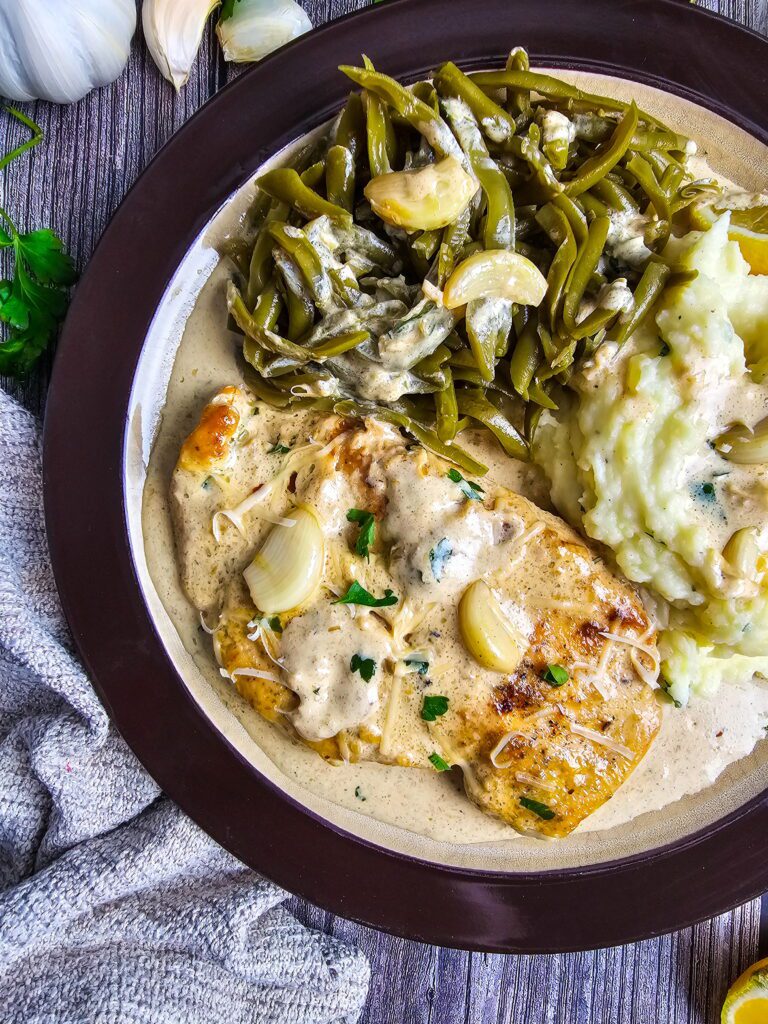 Close-up of restaurant style creamy garlic chicken skillet showing glossy parmesan garlic cream sauce coating the cutlets