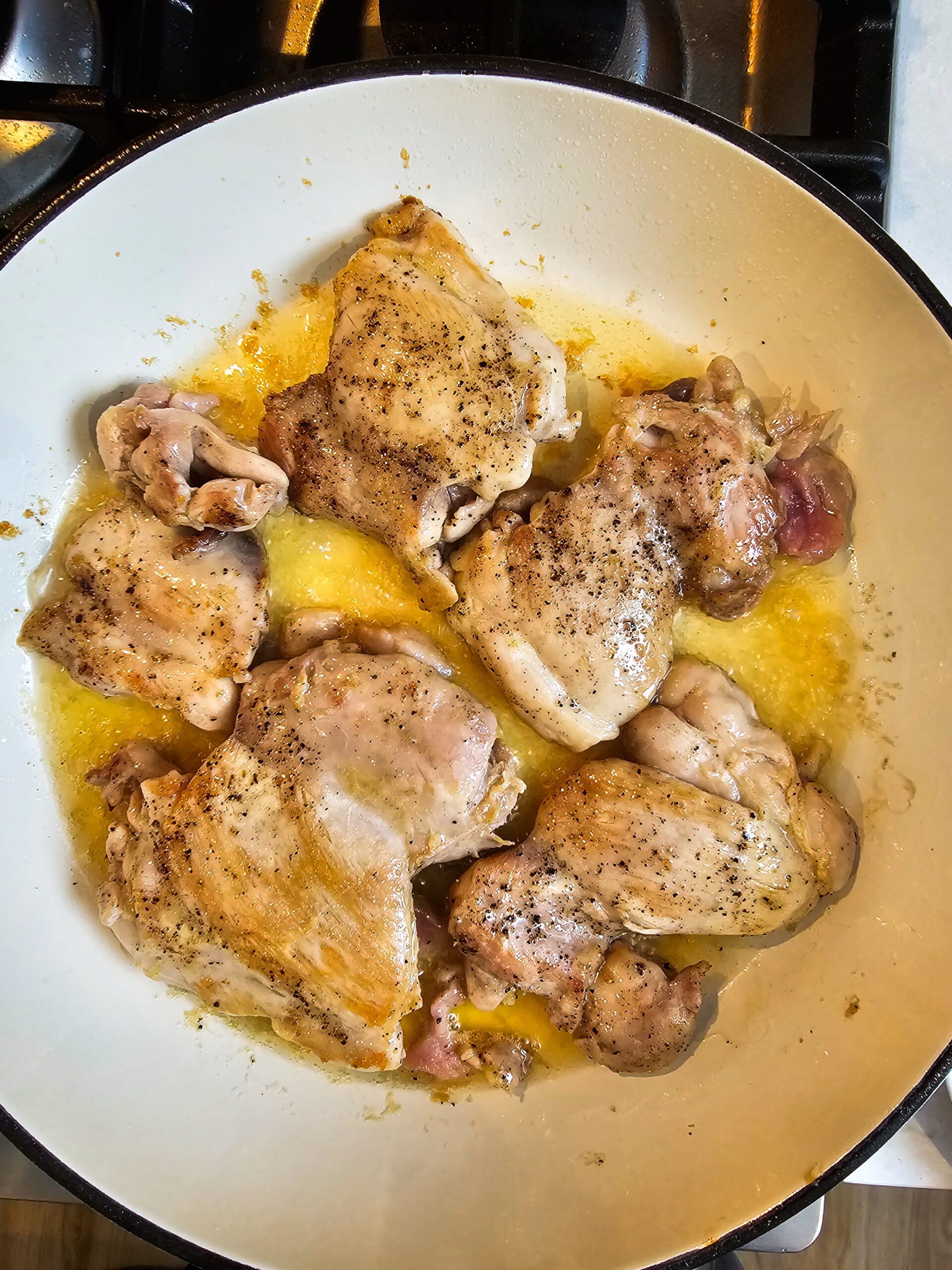 chicken thighs searing in a skillet golden brown