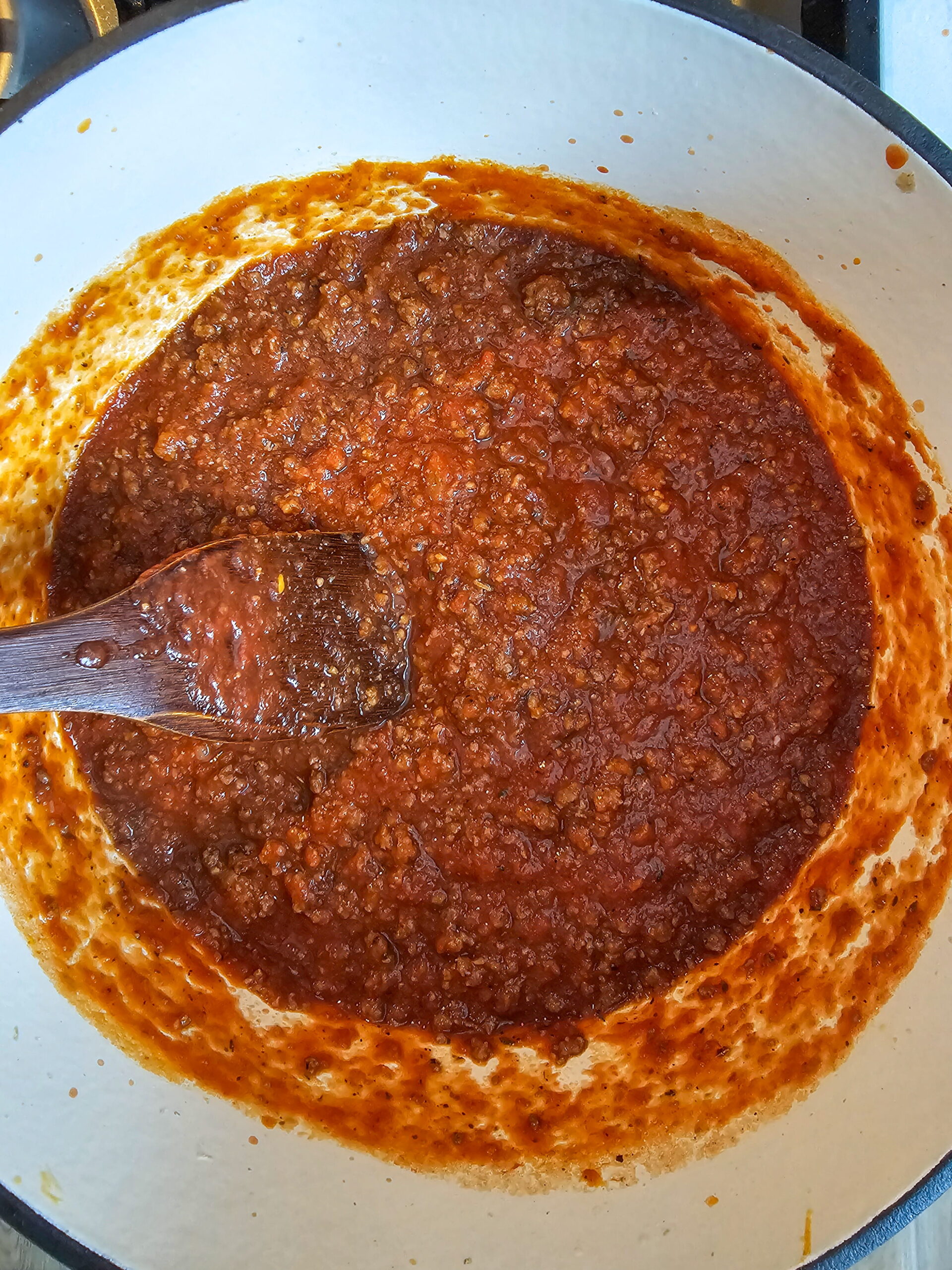 ground beef and onion browning in a skillet with tomato paste being cooked in for deep Italian flavor to make the thick rich sauce