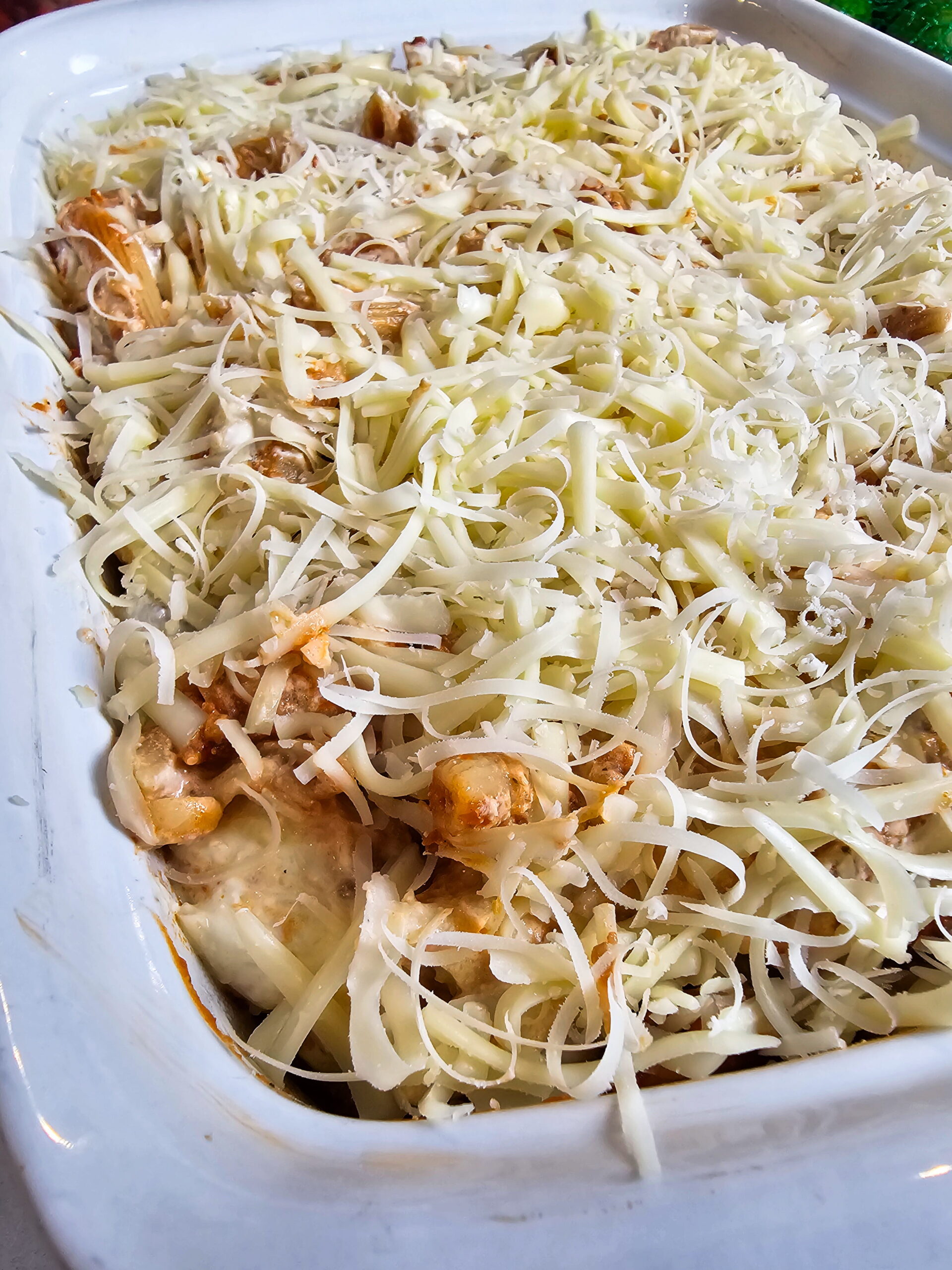 baked ziti topped with shredded mozzarella and parmesan ready to go into the oven at 375 degrees