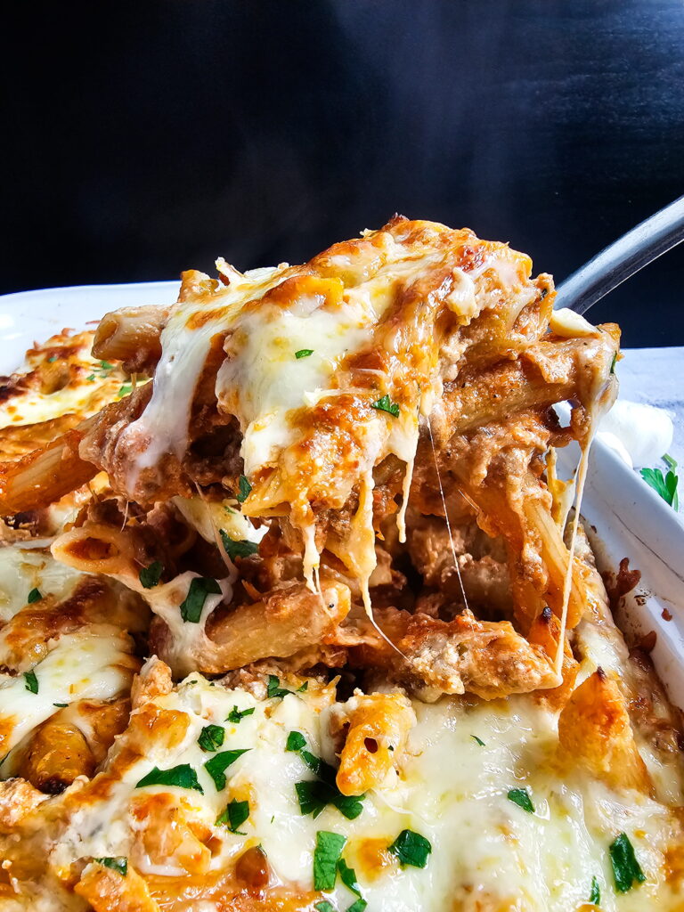 plated baked ziti with ricotta showing scooped with layered meat sauce and golden cheese