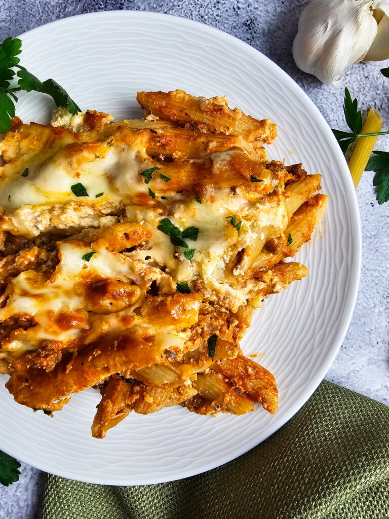 baked ziti with ricotta in a casserole dish with a slice removed showing the clean ricotta layer