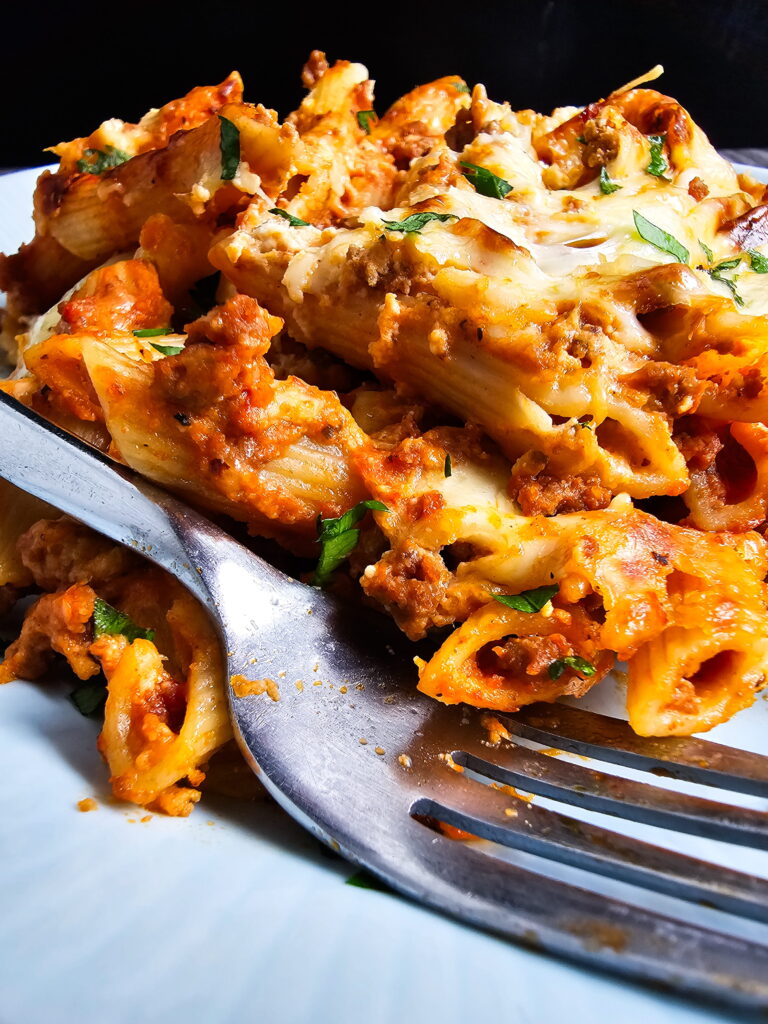 baked ziti with ricotta that holds together — sliced and plated showing golden cheese and rich meat sauce