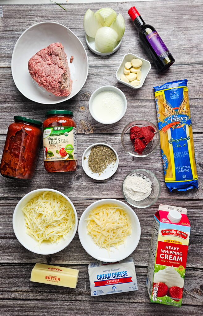 Overhead view of ingredients including ground beef Parmesan cheese heavy cream and mozzarella on a countertop