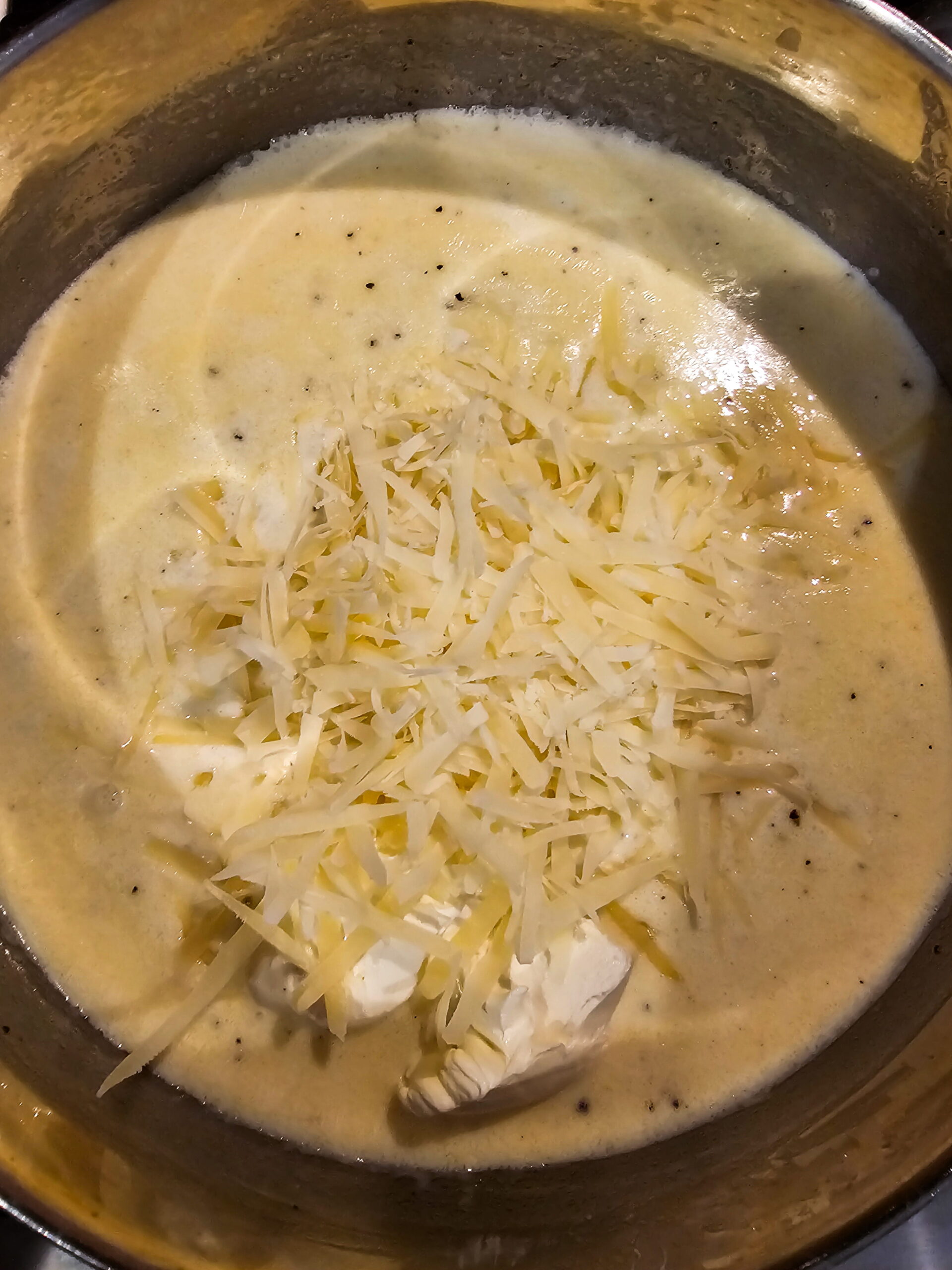 Cream sauce thickening in a saucepan with a whisk resting on the side