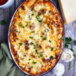 Single serving of baked spaghetti casserole with Alfredo sauce plated with a fork