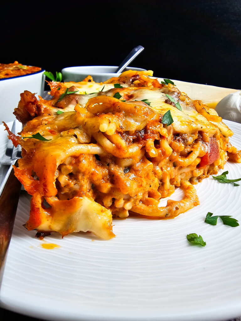 Close-up of a clean scoop of pasta casserole showing distinct cream and meat sauce layers