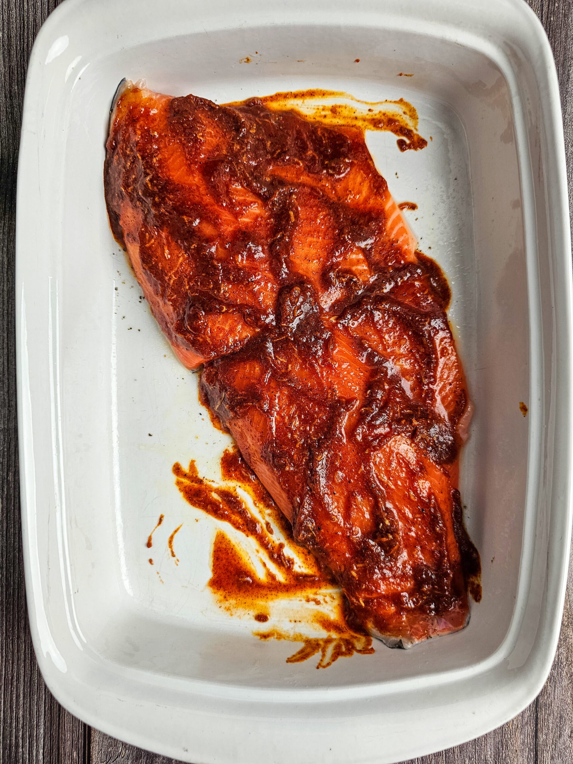 Trout fillets being brushed with chili lime honey glaze on a foil-lined baking sheet before going into the oven