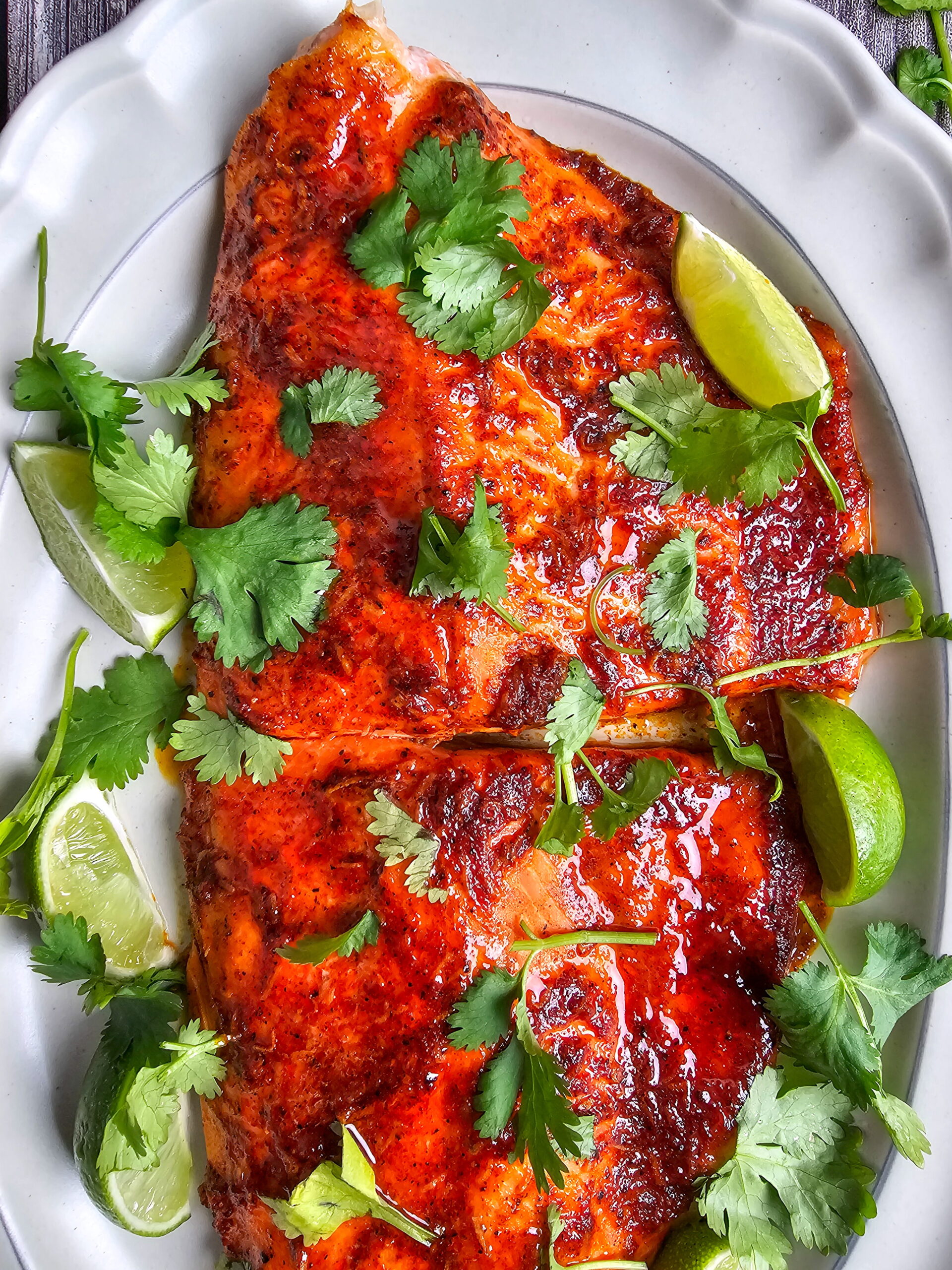 Finished chili lime baked trout fillet plated with fresh cilantro garnish and lime wedge for squeezing