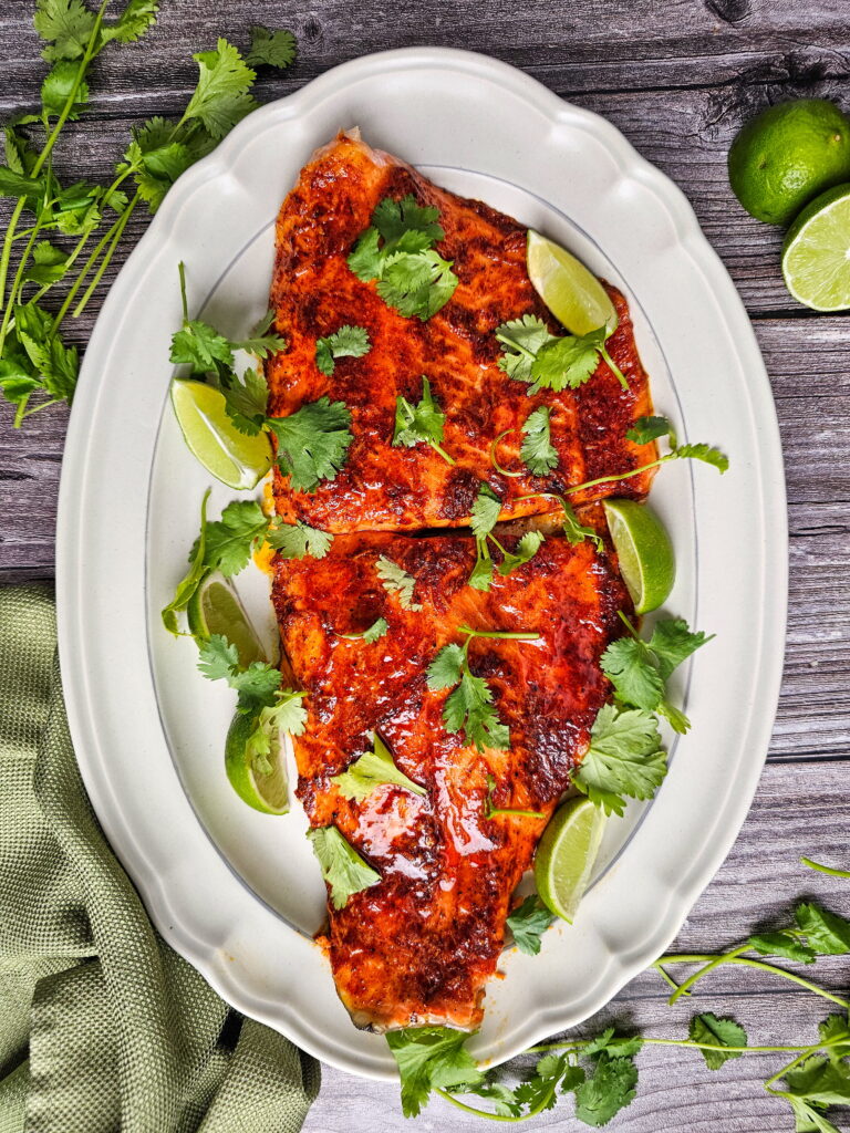 Chili lime baked trout fillets with caramelized honey glaze on a sheet pan, garnished with fresh cilantro and lime wedges